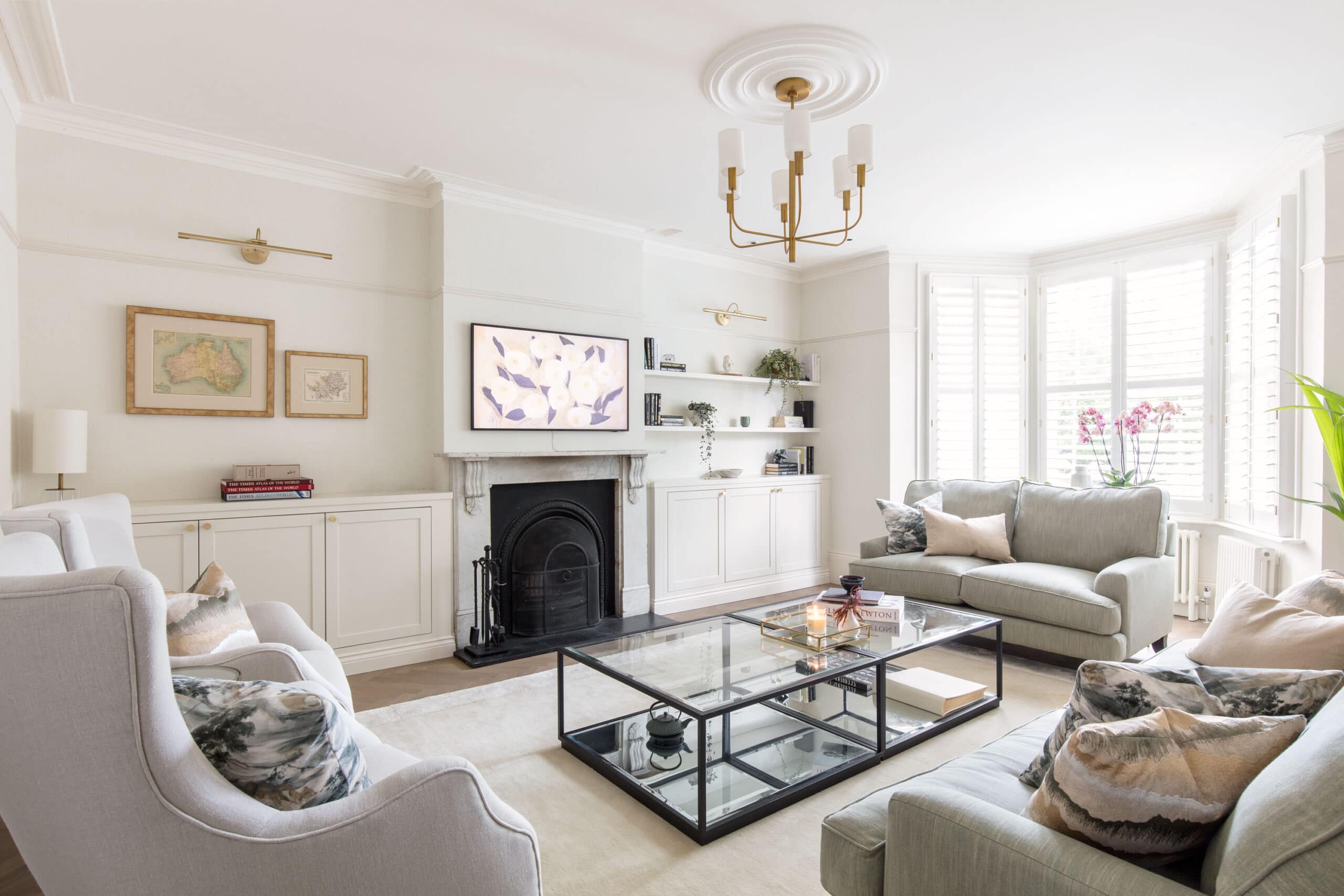 Traditional family sitting room in a St Albans renovation, with restored cornice, marble fireplace and plantation shutters in the bay window showcases Randa Kort Interior Design's expertise in luxury interior design, space planning, and home extensions in St Albans, Hertfordshire.
