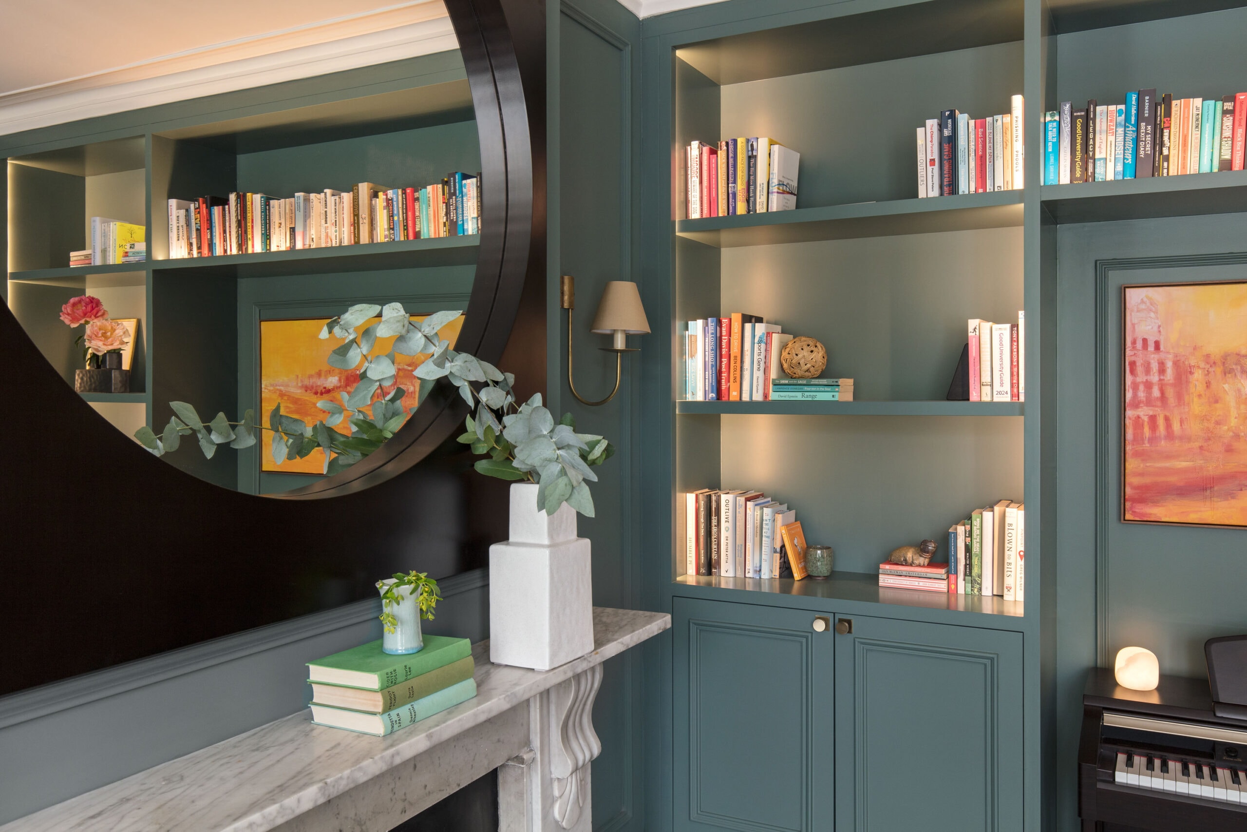 Randa Kort Interior Design showcases a sophisticated home library with built-in bookshelves in St Albans, Hertfordshire, highlighting space planning and interior styling. Restored cast iron and marble fireplace framed by bespoke green cabinetry and a piano in a St Albans study renovation.