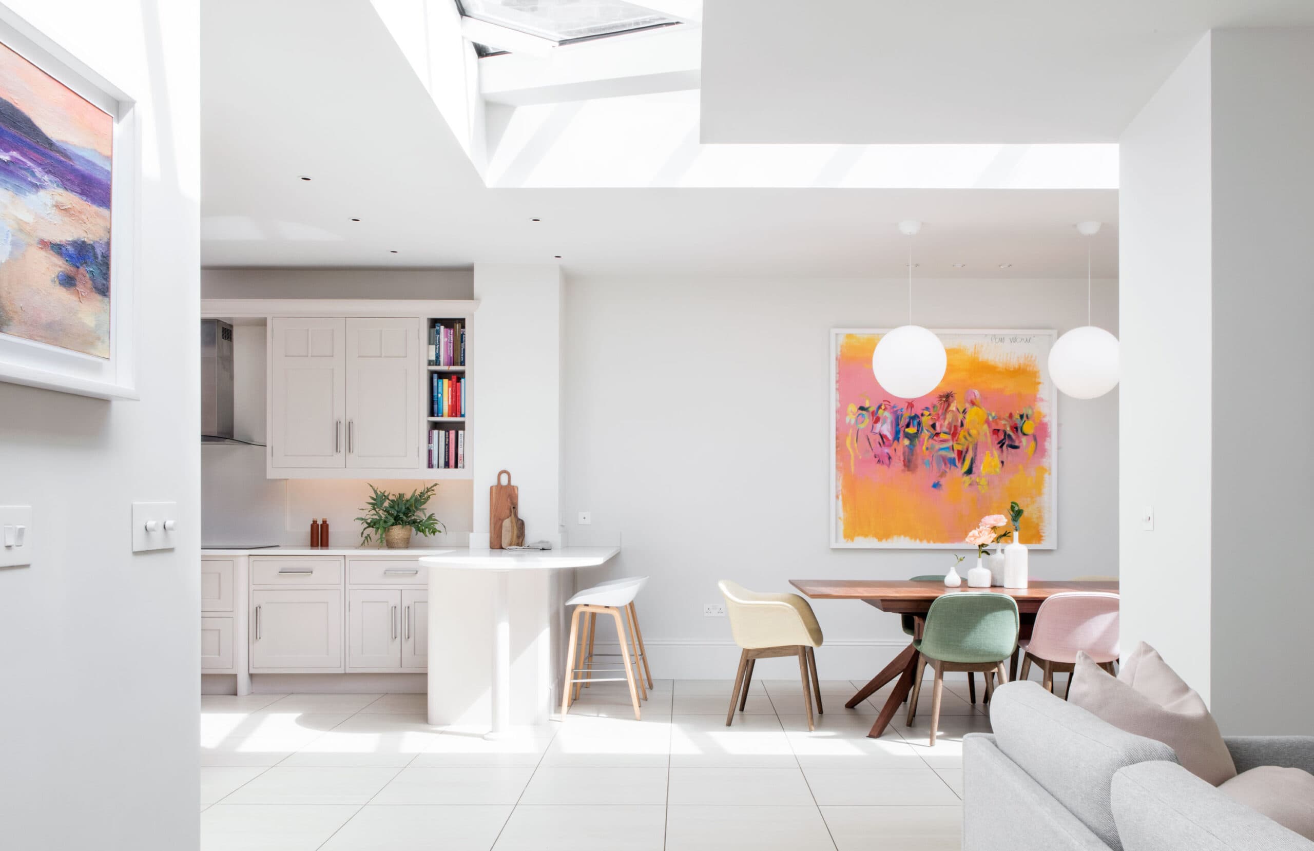 Contemporary open plan kitchen and dining space in St Albans, with pale shaker cabinetry, walnut dining table and globe pendant lights.
