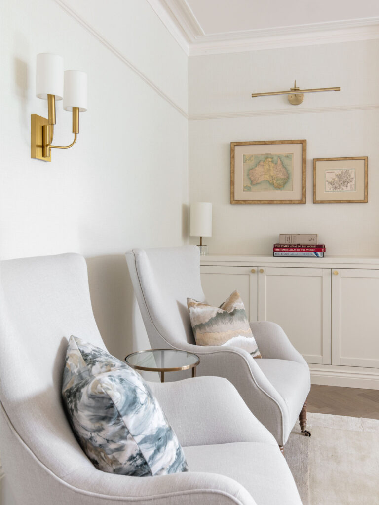 Elegant pale sitting room in a St Albans period home, with panelling, brass wall lights and soft neutral furnishings designed by Randa Kort Interior Design in St Albans, Hertfordshire.