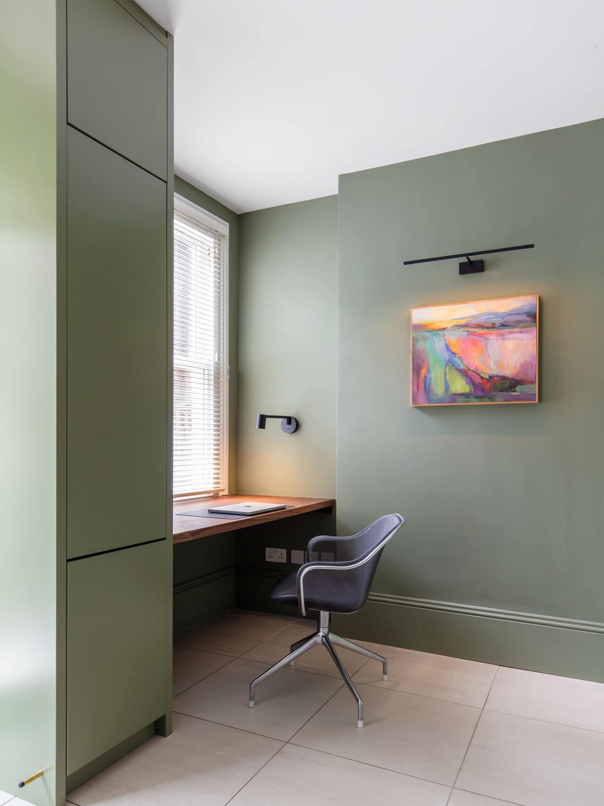 Bespoke sage green study with a built in walnut desk and colourful artwork in a St Albans home renovation. Designed by Randa Kort