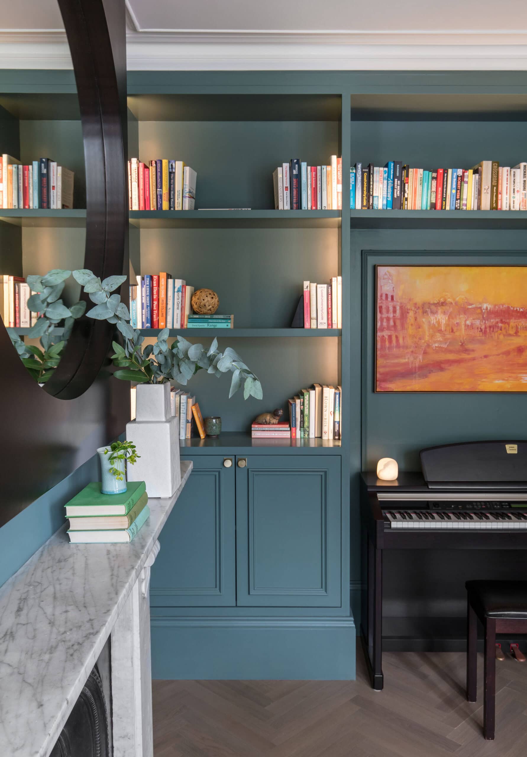 Randa Kort Interior Design created a sophisticated home library in St Albans, Hertfordshire, featuring custom bookshelves, elegant cabinetry, and a stylish piano.